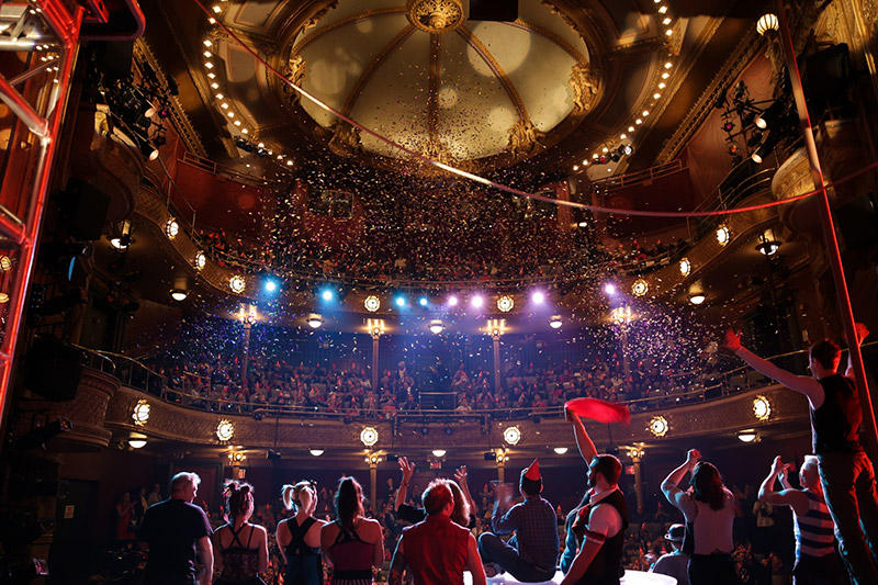 Audience celebrating New Victory's 20th anniversary with confetti, festive lighting and streamers.