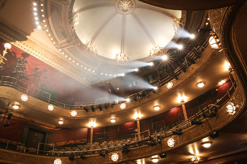 Interior of the New Victory Theater with stage lights in balcony.