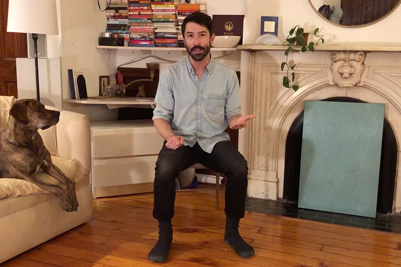 Man in chair leading body percussion activity in his apartment