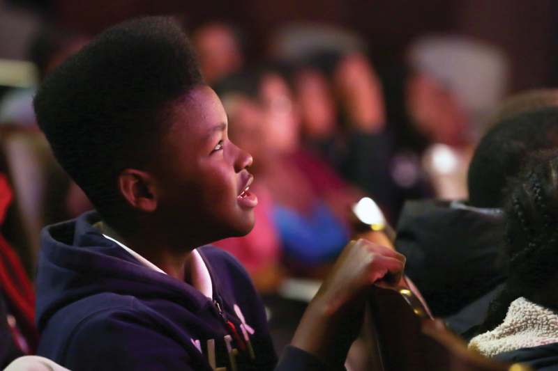 A young boy watches a performance in awe