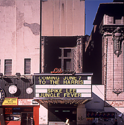 Dilapidate Liberty Theatre Marquee reads Spike Lee, Jungle Fever next to a sign Peep Land Nude Dancing Girls and Exotic, Exciting, Erotic