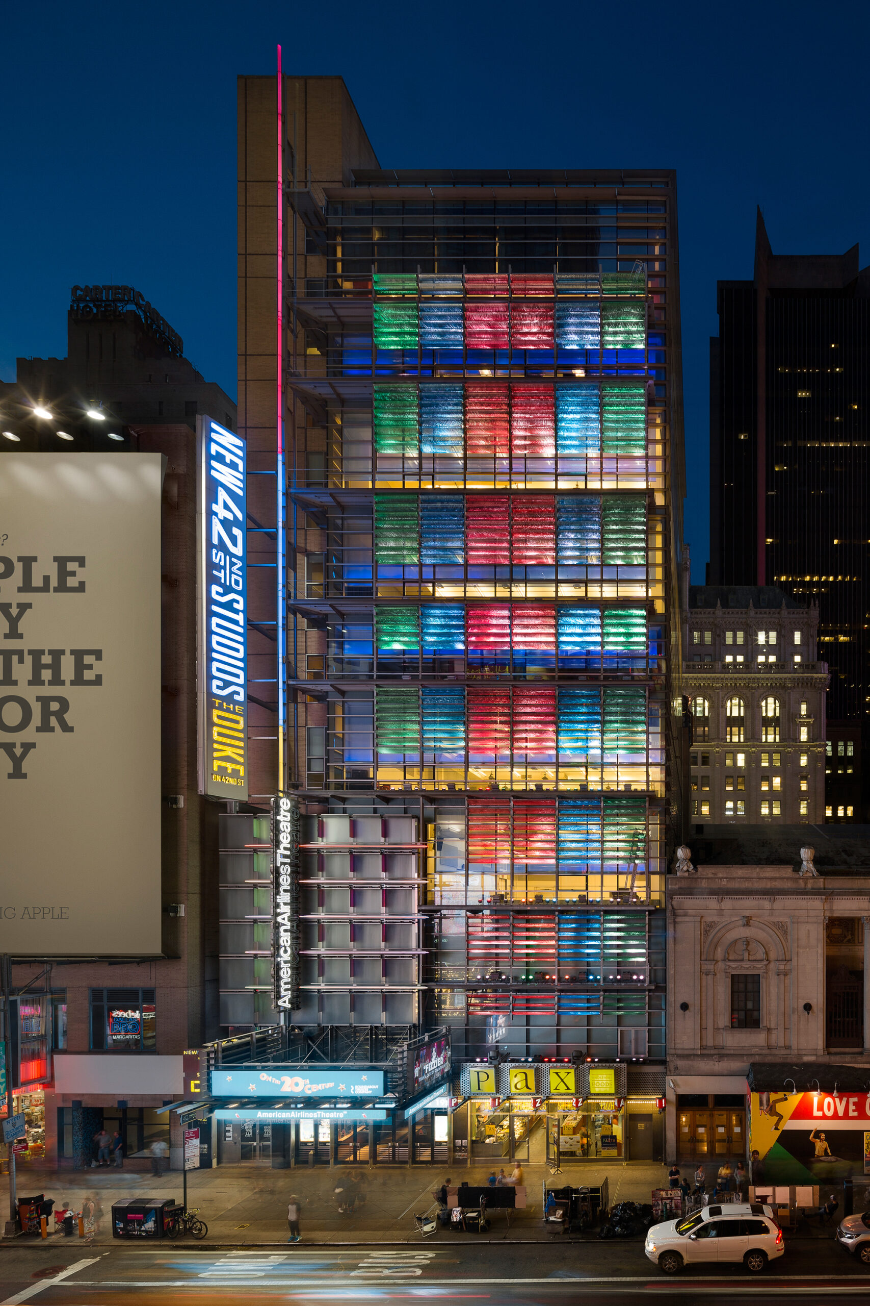 Exterior of New 42 Studios lit up in alternating bands of color at night