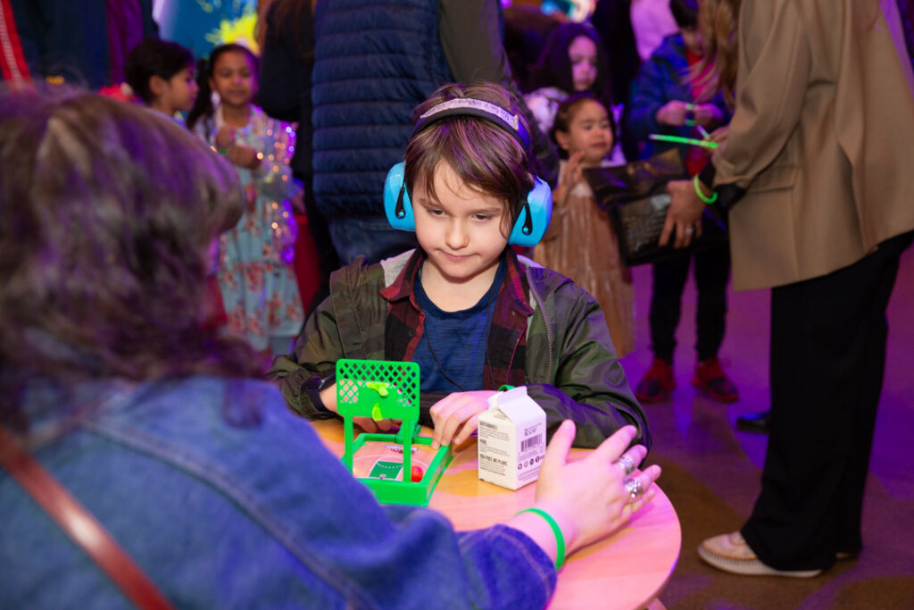 kid wearing ear defenders and doing an activity.