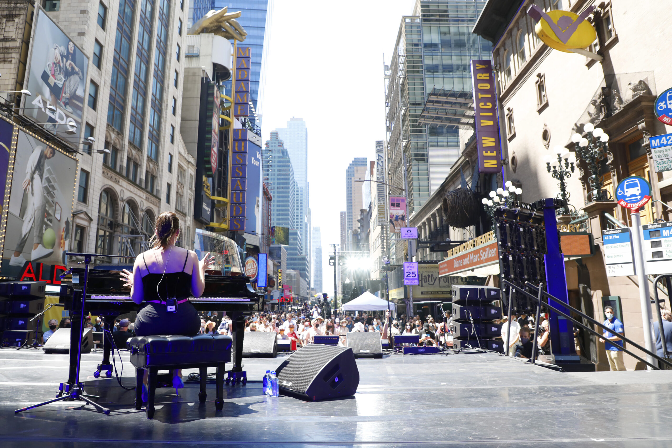 Sara Bareilles plays piano on outdoor stage on 42nd Street as crowd looks on