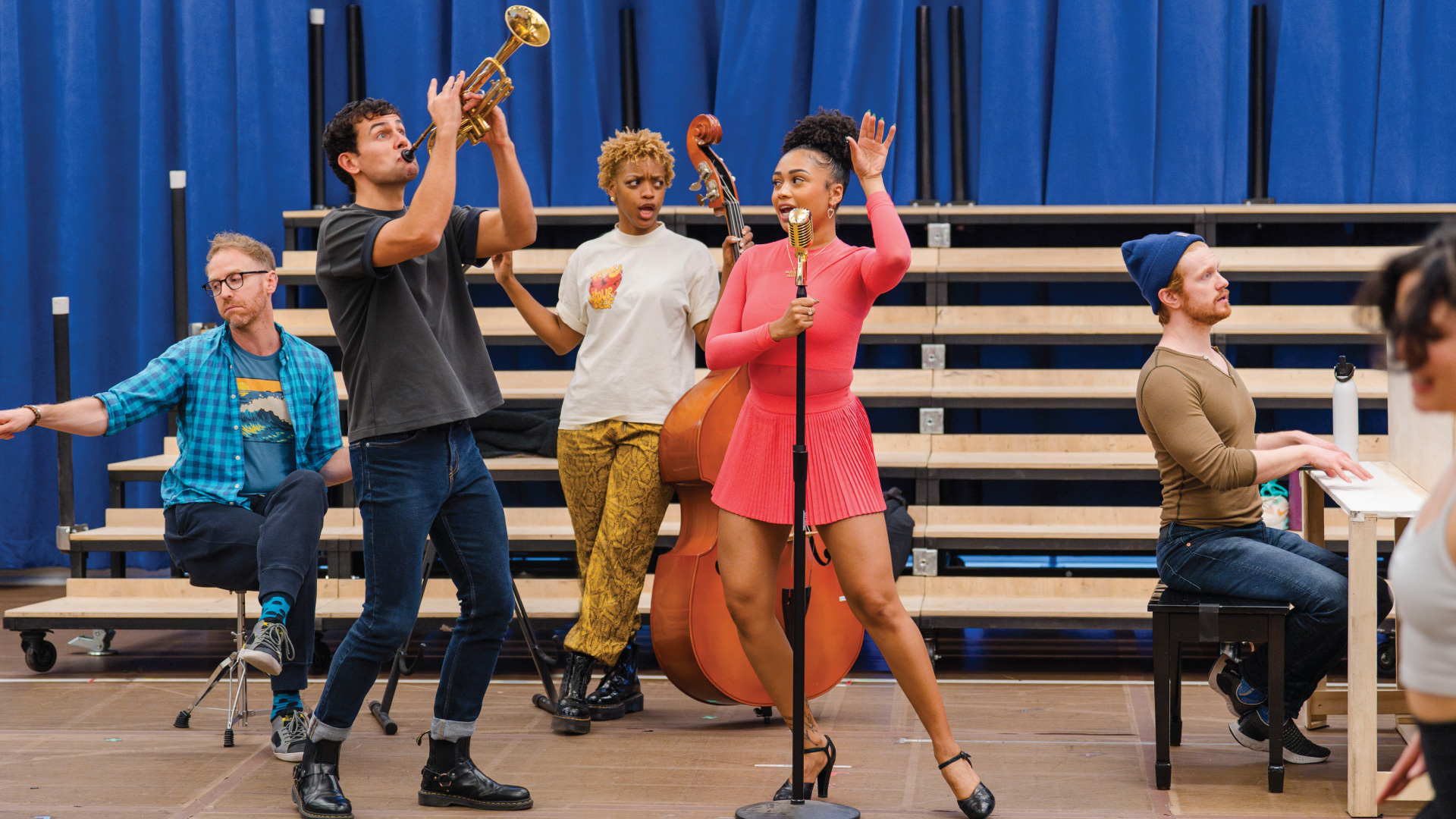 Trumpet player, base player and pianist flank singer at standing microphone
