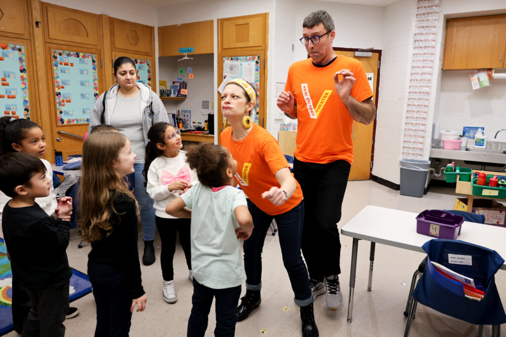 Teaching artist playing around with children in a classroom.