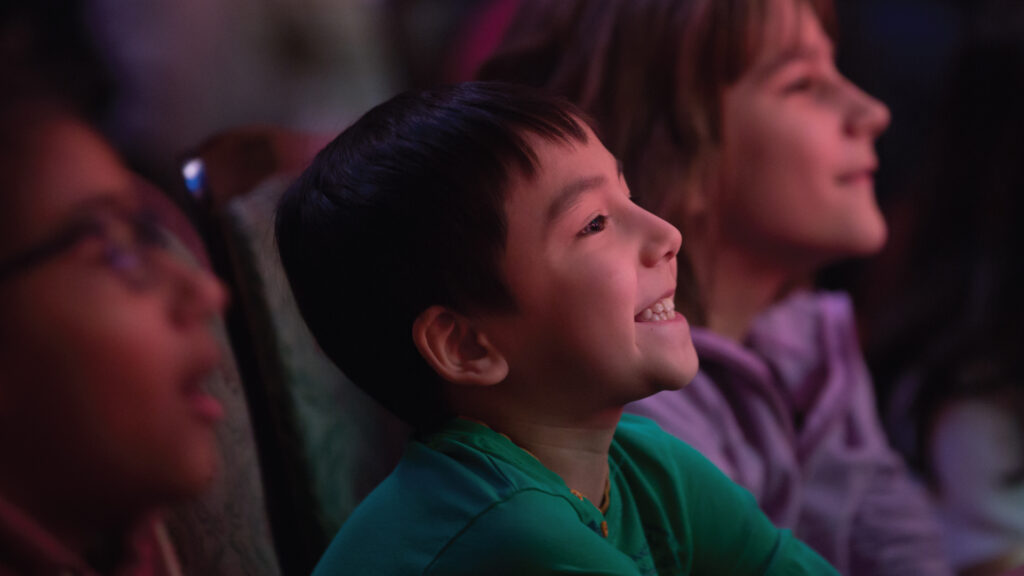 A kid wearing a green shirt smiling up at the stage