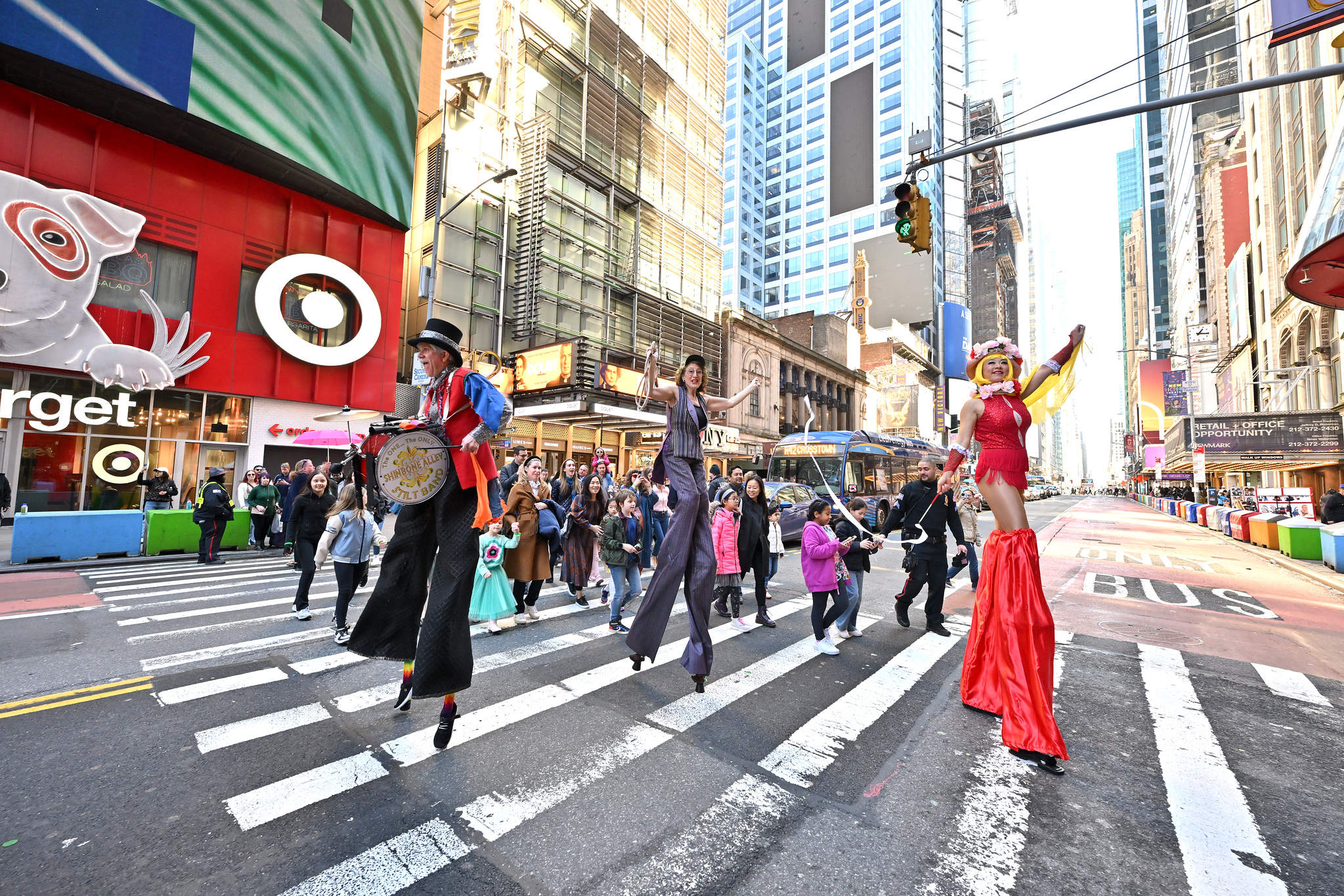 Three stilt walkers lead a parade across 42nd street